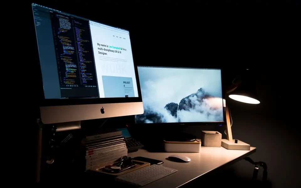 Karanlık çalışma masasında monitörde kod ve web sitesi tasarımı