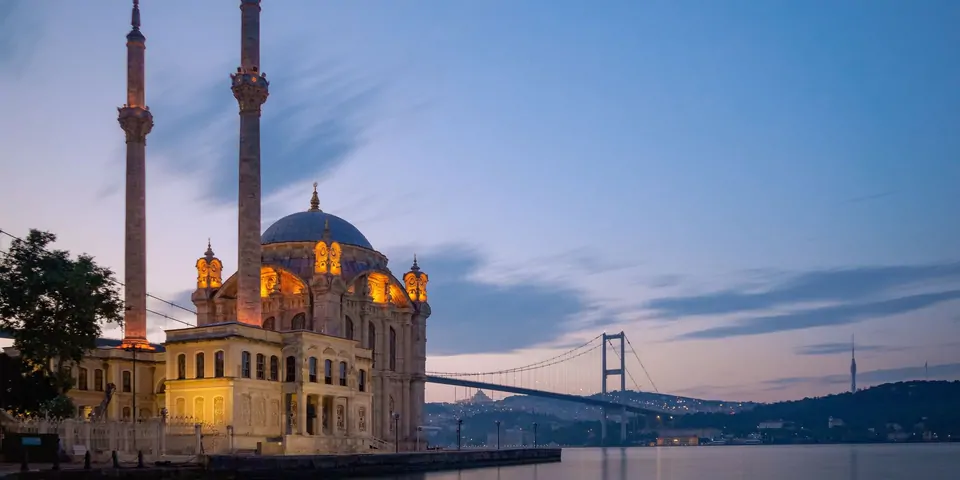 Alacakaranlıkta ışıklandırılmış Ortaköy Camii ve arkasında 15 Temmuz Şehitler Köprüsü