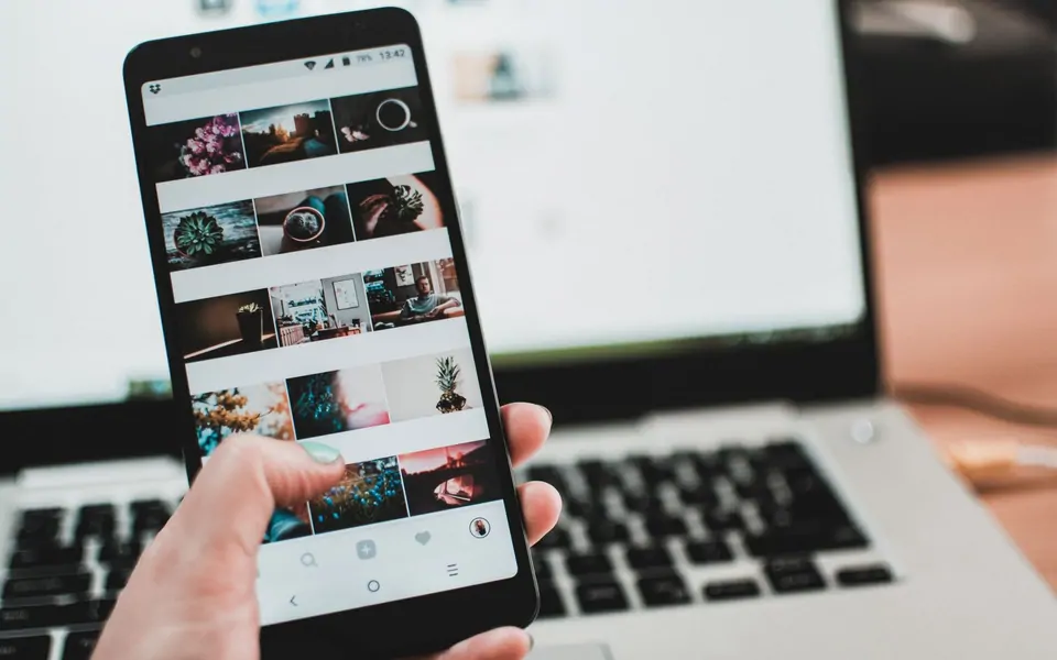Dizüstü üzerinde elde tutulan telefonda fotoğraf akışı